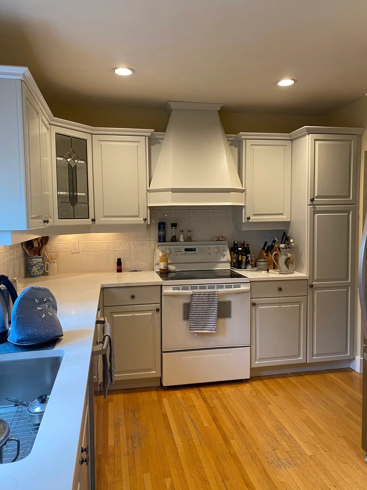 Cream cabinet doors, glass inserts, and a matching hood surround.
