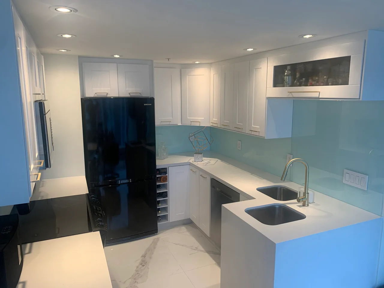 White shaker kitchen doors with brass-tone handles and pale blue backsplash