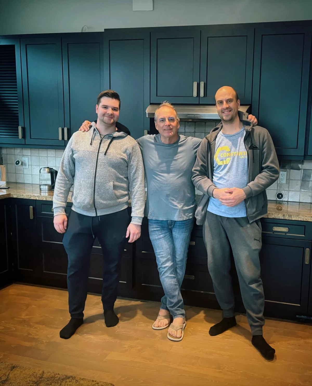 Konstantin with client Michael and another person beside dark teal cabinetry